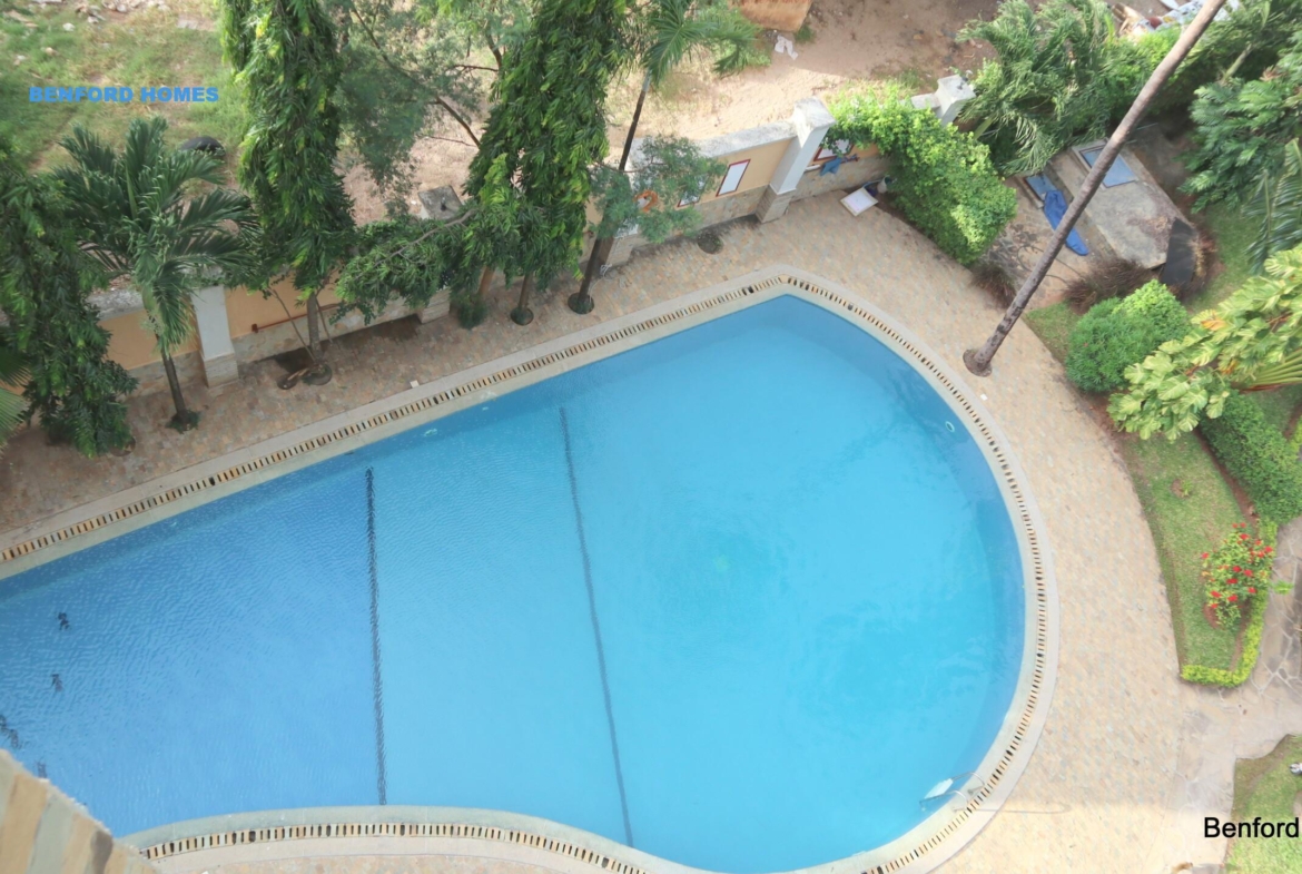 P-shaped swimming pool with tree lined compound and high rise apartments| Benford Homes
