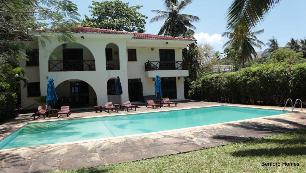 Outdoor swimming pool with a garden and trees in a luxurious 4 bedroom villa| Benford Homes