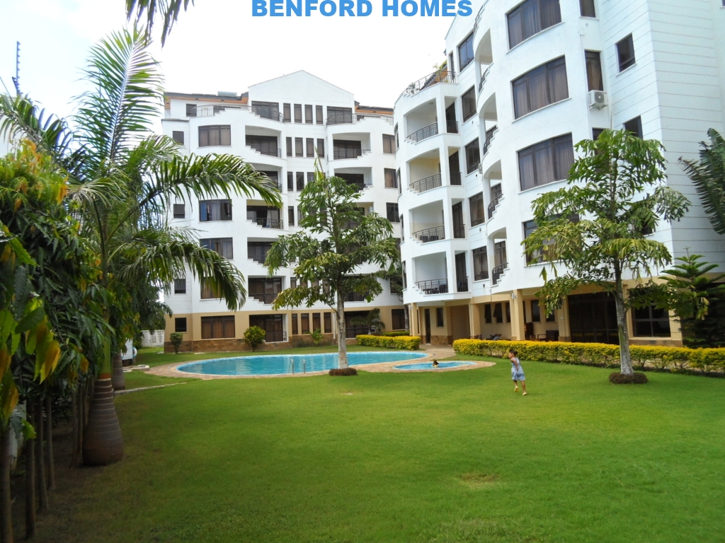 Front view of 3 bedroom apartment by Benford Homes in Nyali with pool while kid is playing on on the well trimmed grass