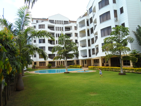 Front view of 3 bedroom apartment by Benford Homes in Nyali with pool while kid is playing on on the well trimmed grass